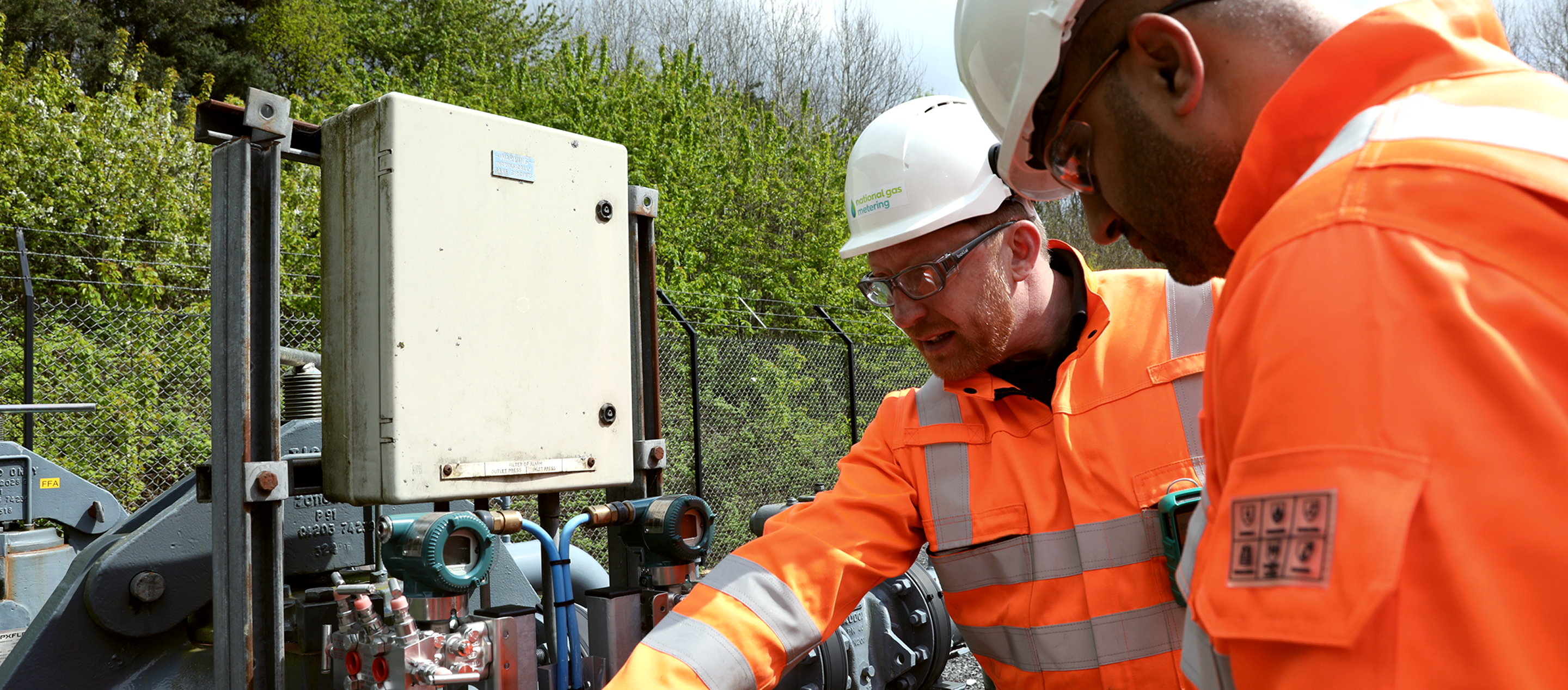 Two National Gas Metering engineers in PPE inspecting outdoor gas equipment and instrumentation.