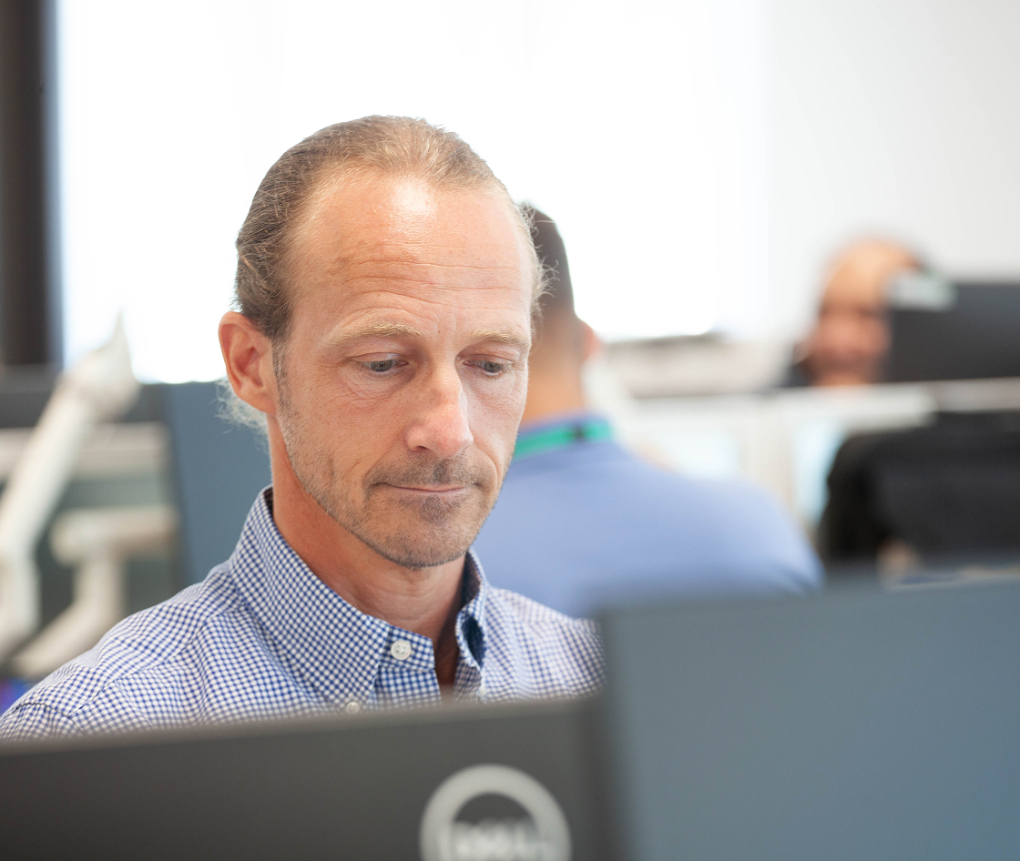 Man focused on his work at a computer in a modern office environment.