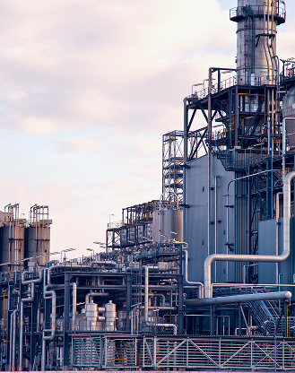 Exterior view of a large industrial facility with extensive pipework and towers.