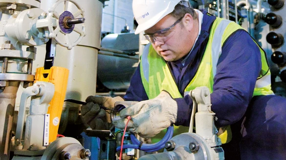 A close up of a National Grid worker performing maintenance with industrial equipment in the background 