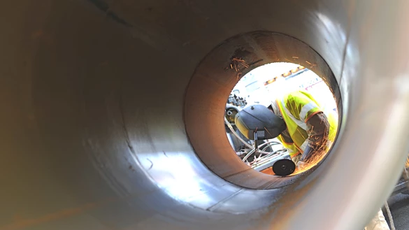 A view through a tunnel structure to a National Grid employee performing maintenance at the other end 