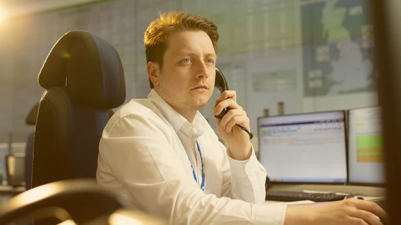 A National Grid worker on the phone with various data screens on display in the background 