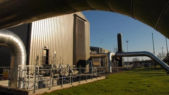 Partial view of a gas industry site with grass in the foreground and a blue sky in the background