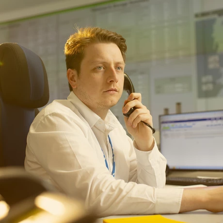 A National Grid worker on the phone with various data screens on display in the background 
