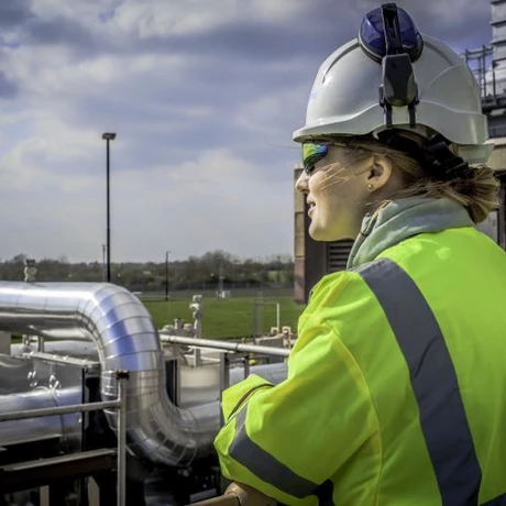 A National Grid worker looking out with an industrial building and a blue sky in the background 