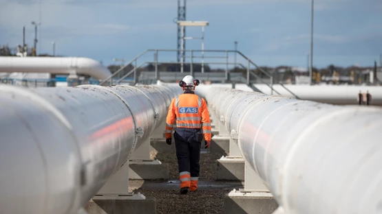 Person wearing Gas branded PPE walking between gas pipelines at St Fergus gas terminal in Scotland