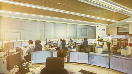 A wide view of National Grid workers and data display screens inside a GNCC office space 