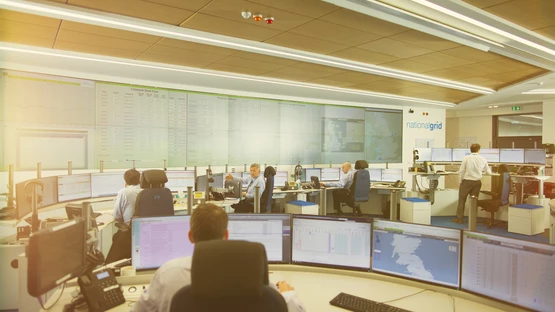 A wide view of National Grid workers and data display screens inside a GNCC office space 