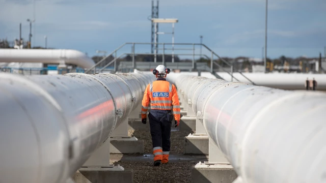 Person wearing Gas branded PPE walking between gas pipelines at St Fergus gas terminal in Scotland