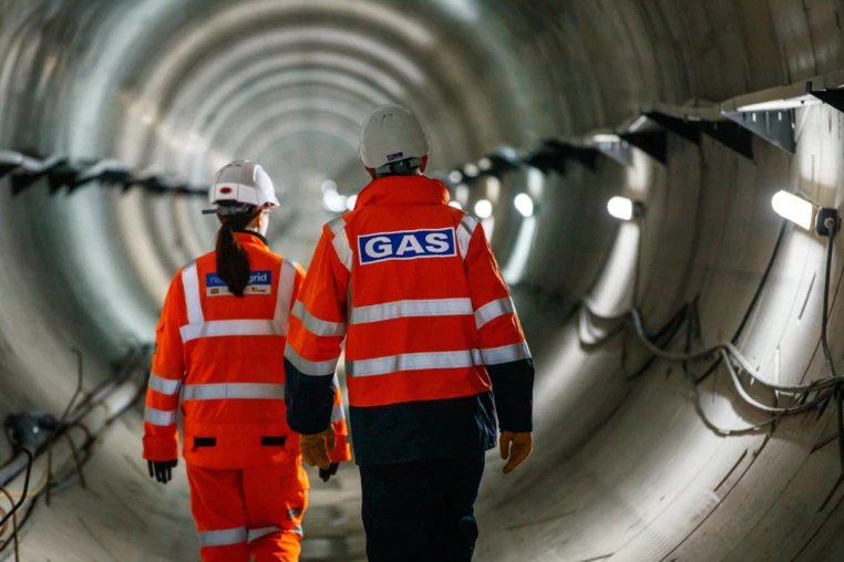 Two workers walking through pipeline