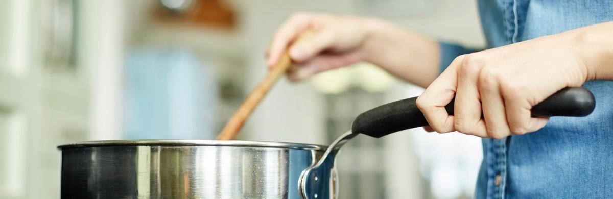 A pan being stirred on a hob with an out of focus kitchen in the background 